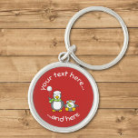 Porte-clés Christmas Snowballing Penguins Keychain<br><div class="desc">A little penguin cartoon with snowball and a fainted one. Both wearing green scarfs and santa hats. Custom background color. Custom text.</div>