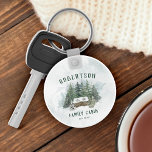 Porte-clés Famille Cabine Pins de Forêt Personnalisé<br><div class="desc">Ce porte - clé cabine familial personnalisé présente une scène aquarelle rustique d'un cabine niché dans la forêt de pins enneigés,  avec nom de famille et année établie.</div>