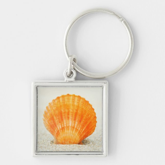 Porte-clés Feston Shell orange se tenant droit en sable (Devant)