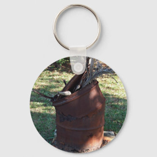 Porte-clés Poubelle rouillée dans un paysage herbeux