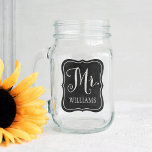 Pot Mason M. Rustic Script Monogram Chalkboard Mariage<br><div class="desc">Le design personnalisé de bocal en mariage en maçon comporte M. en écriture blanche avec du texte personnalisé pour le nom de famille du marié. Le cadre décoratif a un arrière - plan à l'aspect texturé en damier noir. Design recto-verso.</div>