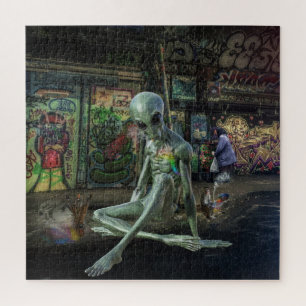 PUZZLE GREEN GREY ALIEN SITTING ON PAVEMENT WITH GRAFFITI