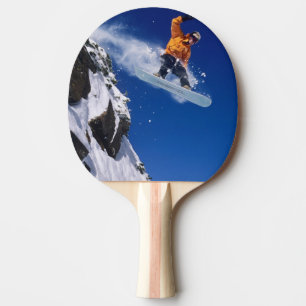 Raquette De Ping Pong Homme sur un snowboard sautant d'une corniche à