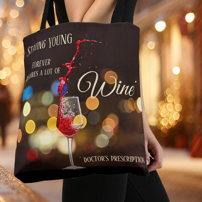 Sac fourre-tout étincelant de vin léger (Tote bag with a wine theme featuring a glass of swirling wine on a sparkling light night scene )
