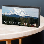 Signe En Bois Bienvenue au paysage pittoresque du Mont Rainer<br><div class="desc">Maison accueillante, panneau en bois conçu pour être suspendu ou debout, avec une photo de paysage pittoresque du Mont Rainier recouvert de neige et une vallée verte dans l'état de Washington du Nord-Ouest du Pacifique. Des lettres brunes et blanches disaient : "BIENVENUE À NOTRE MAISON." Choisissez parmi le bois peint...</div>