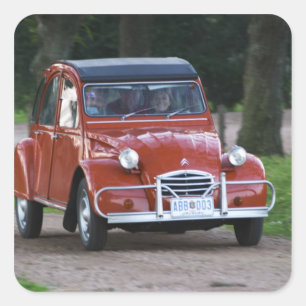 Sticker Carré Une vieille voiture rouge Citroen 2CV avec une fem