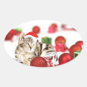 Sticker Ovale Chat portant un ornement de Noël au chapeau rouge