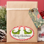 Sticker Ovale Jolly Christmas Elf Legs Vacances OVAL<br><div class="desc">Pieds elfes amusants portant des collants rayés rouge et ivoire et des bottes vertes avec des cloches de jingle, et vos détails de Noël de vacances en lettres chic, ces autocollants OVAL sont beaux pour les faveurs de fête, les cadeaux, les enveloppes d'invitation, les cadeaux alimentaires faits maison et plus...</div>