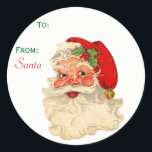 Sticker Rond À partir de Santa Claus Face Christmas tag<br><div class="desc">Balise de Noël préimprimée "From Père Noël". Il présente un visage classique de Noël joyeux avec des joues roses. Il porte son casquette rouge avec un sanglier de saint et une cloche dorée à la fin. Amusant et festif pour adultes et enfants. Options, le mot Père Noël peut être supprimé...</div>
