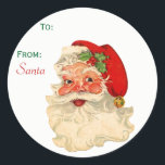 Sticker Rond À partir de Santa Claus Face Christmas tag<br><div class="desc">Balise de Noël préimprimée "From Père Noël". Il présente un visage classique de Noël joyeux avec des joues roses. Il porte son casquette rouge avec un sanglier de saint et une cloche dorée à la fin. Amusant et festif pour adultes et enfants. Options, le mot Père Noël peut être supprimé...</div>