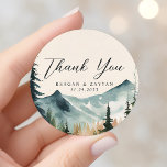 Sticker Rond Aquarelle Montagnes Et Pins Mariage Merci<br><div class="desc">Express votre gratitude avec la beauté paisible des Monts Watercolor et Pines Mariage Merci Classic Round Sticker. Cet autocollant, imprimé sur un matériau durable, présente une scène d'aquarelle sereine de montagnes et de pins. Un message de "Merci" sincère, écrit dans la typographie moderne, accapare le centre de l'autocollant. Parfait pour...</div>