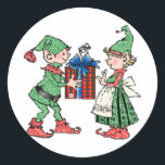 Sticker Rond Cadeau Vintage Christmas Elves Giving<br><div class="desc">Une adorable paire d'elfes à Noël. Le garçon elf donne à la fille un grand cadeau enveloppé d'un gros arc.</div>