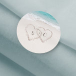 Sticker Rond Coeurs dans le sable destination mariage plage<br><div class="desc">Il comprend deux coeurs dans le sable et les initiales de la mariée et du marié avec l'eau turquoise et l'arrière - plan de plage de sable blanc,  idéal pour les mariages de plage d'été,  ou mariage de destination tropicale.</div>