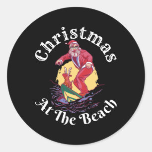 Sticker Rond Noël à la plage drôle de Père Noël surfant avec Re