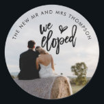 Sticker Rond Nous Avons Elopé Photo Nom Artsy Script<br><div class="desc">Pratique pour vos mailings après votre départ, avec votre photo préférée de vous tous les deux de votre jour que vous téléchargez simplement pour remplacer l'échantillon. La typographie est superposée. Nous Eloped est dans un ensemble d'art moderne avec un motif de coeur, et simple sans texte est courbé autour du...</div>