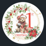 Sticker Rond Ours Poinsettia Foliage Baby's First Christmas<br><div class="desc">Ce design présente un ours en peluche de Noël avec chapeau de Père Noël et présente à l'intérieur de la couronne de Noël avec poinsettia,  feuillage verdoyant et baies rouges. Vous pouvez ajuster le texte en fonction de vos besoins.</div>