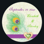 Sticker Rond Peacock plumes bijou coeur mariage Enregistrer la<br><div class="desc">Mariage coeur de bijoux en plumes de paon Enregistrer l'autocollant Date, avec une élégante plume paon en chaux et vert émeraude, violet et orange, une bande violette et une illustration d'un diamant de bijoux en coeur vert avec contour en or avec strass sur arrière - plan damassé en ivoire écru....</div>
