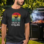T-shirt Barbecue de graissage et de refroidissement<br><div class="desc">Avec un barbecue sur des bandes colorées et les mots "Grilling and Chilling",  ce t-shirt est un cadeau parfait pour les hommes de votre vie,  pour la fête des pères,  Noël ou son anniversaire. CORRESPONDANCE d'objets dans notre collection.</div>