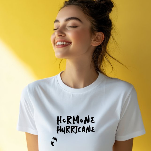 T-shirt Empreinte de bébé de grossesse humoristique noire (Accompanying this striking visual is the lighthearted and amusing phrase "Hormone Hurricane,")