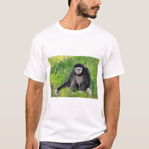 T-shirt Gibbon à main blanche assis sur l'herbe