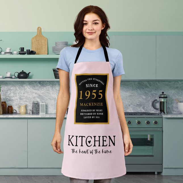 Tablier 70e Anniversaire Cuisine Queen Coeur de maison ros (Personalized 70th birthday apron worn by a woman in the kitchen)