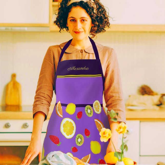 Tablier Fruits d'été frais Apron (A woman in a kitchen wearing a beautiful purple apron decorated with lemons, kiwis, strawberries)