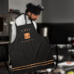 Tablier Monogramme élégant noir nom du script chef<br><div class="desc">Monogrammed élégant luxe cuisine exclusive restaurant principal tablier chef avec un faux carré de parties scintillant métallique en cuivre or et lignes sur un élégant arrière - plan en faux cuir noir (TEXTURE IMPRIMÉE) classe.              Personnalisez-le avec le titre,  le nom et les initiales.</div>