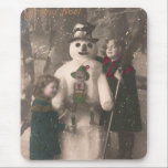 Tapis De Souris Photo de Christmas Girls et Snowman Vintage<br><div class="desc">A charming antique 1910 French Christmas photo postcard of two pretty,  adorable little girls happily hugging and posing with their solive snowman friend,  as snow flow down upon them. Wishing a Joyeux Noel.</div>