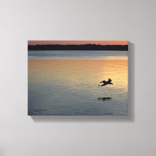 Toile Pelican survolant la rivière au coucher du soleil