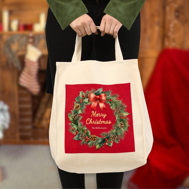 Tote Bag Festif Wreath de Noël Elégant Rouge Personnalisé (An elegant tote bag with festive wreath on a red background, Merry Christmas greeting and custom nam)