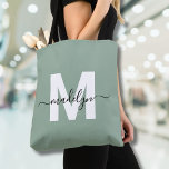 Tote Bag Sage Green Modern Script Nom Monogramme<br><div class="desc">Sage Vert Elégant Personnalisé Moderne tendance Nom de script Monogram Sac fourre-tout. Ajoutez une touche de sophistication à votre style quotidien avec ce sac fourre-tout chic. Doté d'une initiale blanche épurée centrée sur un arrière - plan vert sage doux, revêtu d'un nom de script noir fluide, ce design propre et...</div>