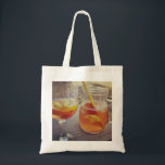 Tote Bag Sangria and Sunshine<br><div class="desc">This image shows a refreshing glass and pitcher of citrus sangria, perfect for a warm day. The fresh slices of lemon and orange add bright colour and hint of natural sweetness. One glass sits ready to enjoy while sangria is being poured from a small glass pitcher beside it, perfect for...</div>