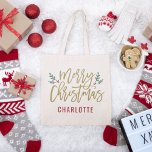 Tote Bag Script Or moderne Joyeux Noël Nom personnalisé<br><div class="desc">Le design élégant du sac fourre-tout de Noël Joyeux présente des branches vertes festives de feuilles saints et des baies rouges accentuent le design moderne de l'écriture or antique. Le texte monogramme personnalisé peut être personnalisé un nom ou un autre texte.</div>