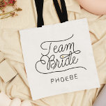 Tote Bag Team Bride Modern Script Gold Nom du Mariage<br><div class="desc">Ce sac fourre-tout moderne avec un design de calligraphie décontracté et chic minimaliste lire TEAM BRIDE ainsi que le nom personnalisé de votre femme de chambre d'honneur ou de demoiselle d'honneur dispose de lignes propres pour créer un aspect élégant et sophistiqué. Le style sobre et le petit détail imprimé du...</div>