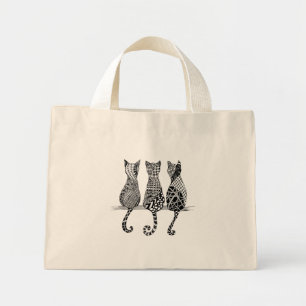 Trois chats noirs et blancs sur un sac