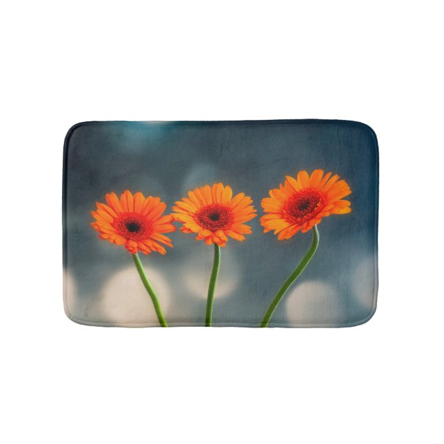 Trois Gerberas orange dans un tapis de bain de ran (Devant)