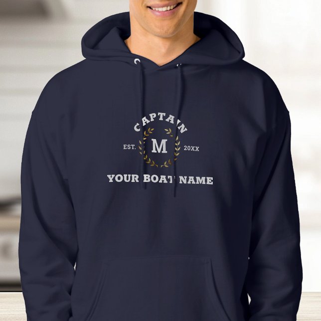 Veste À Capuche Bateau sur mesure Capitaine Monogram Gold Laurel N (A person in a navy hoodie with "Captain" text and laurel wreath design. )